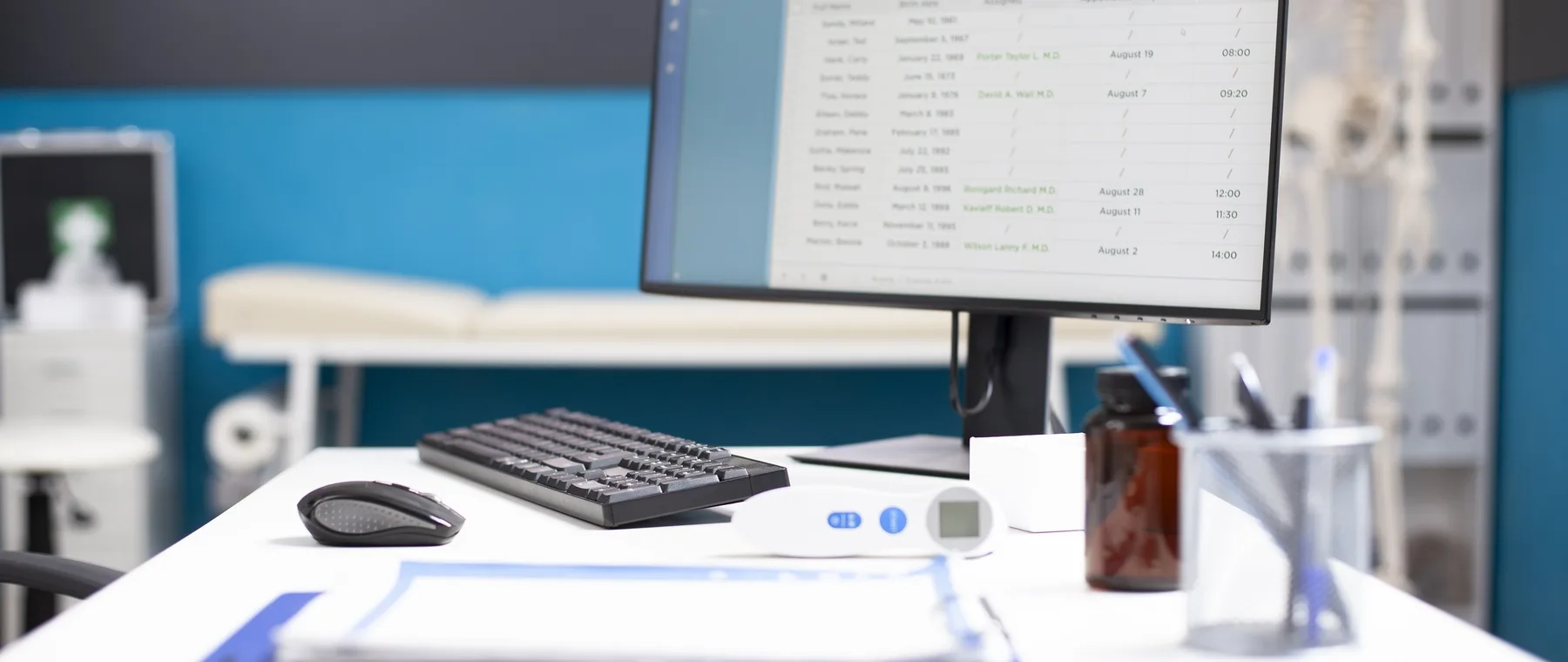 Arbeitsplatz im Behandlungszimmer mit Monitor, Tastatur und medizinischen Instrumenten