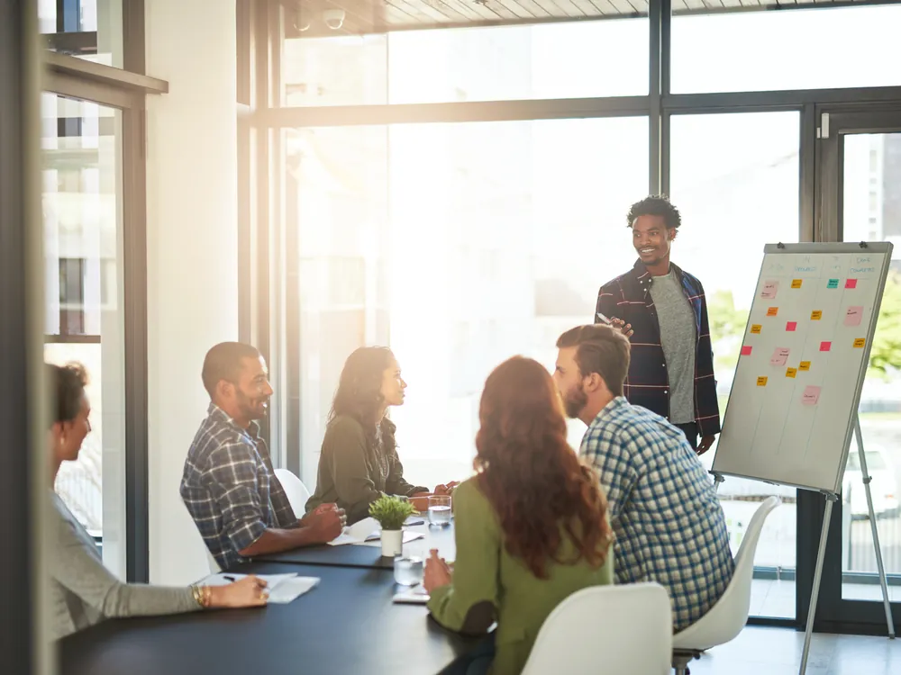 Agenturteam sitzt in einem hellen Besprechungsraum vor einem Flipchart mit Notizzetteln